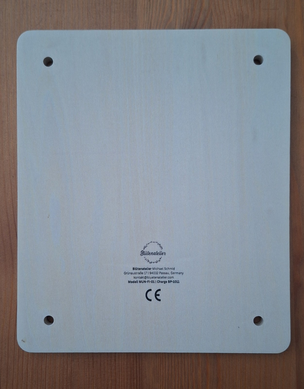Unterseite der unteren Holzplatte mit dem Logo Blütenatelier, der Anschrift des Herstellers, Modell- und Chargennummer sowie der CE-Kennzeichnung.